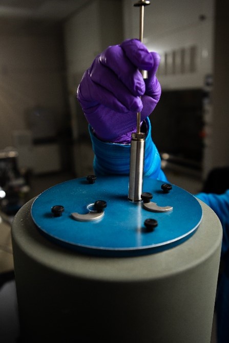 Photograph of gloved hand putting a sample into a calorimeter