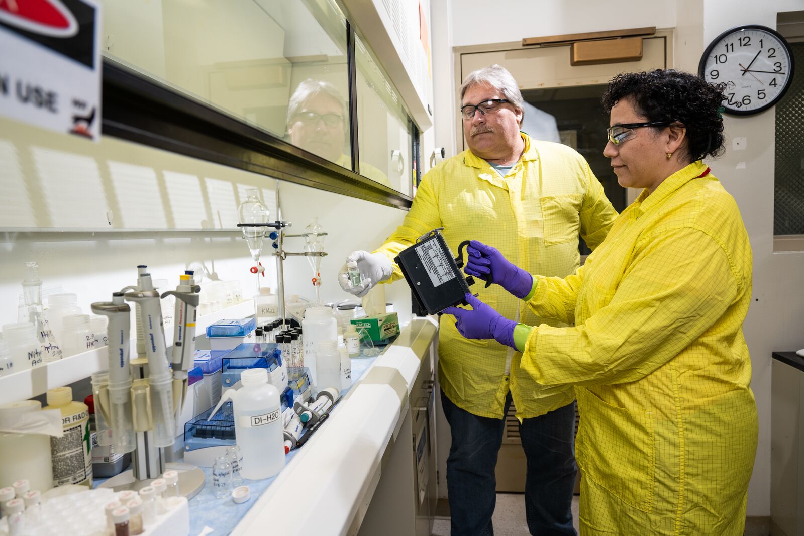 Photo of intern (right) in lab safety gear working with a mentor (left) from the PNNL Radiological Protection Team.