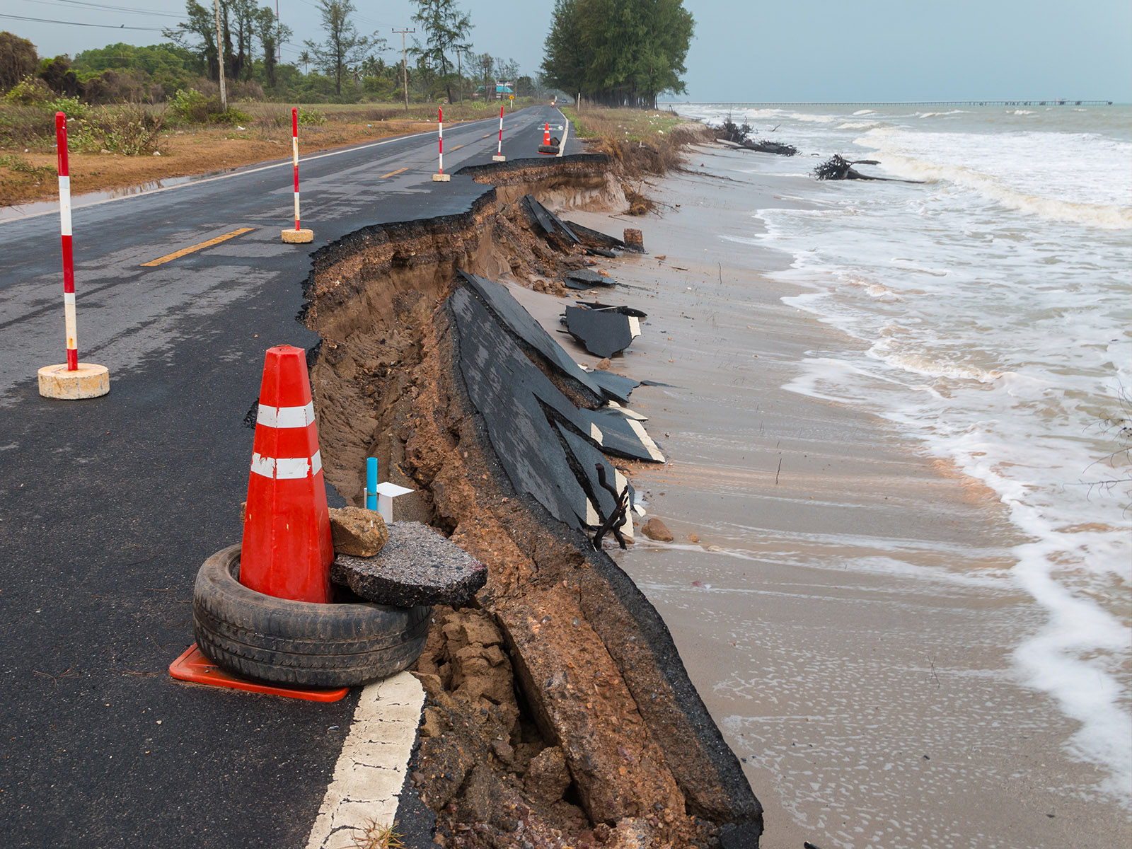 Photo shows rising seas damaging a road next to the water. Climate change poses a threat to infrastructure.