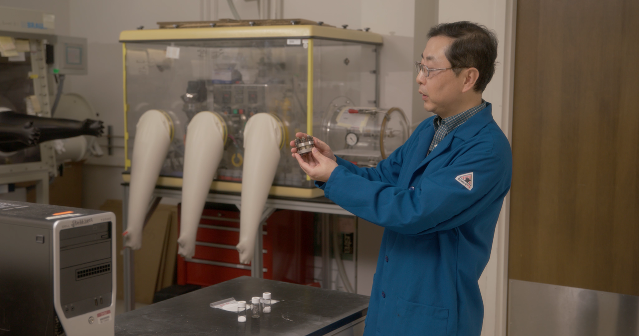 Photo of materials scientist Guosheng Li holding a battery