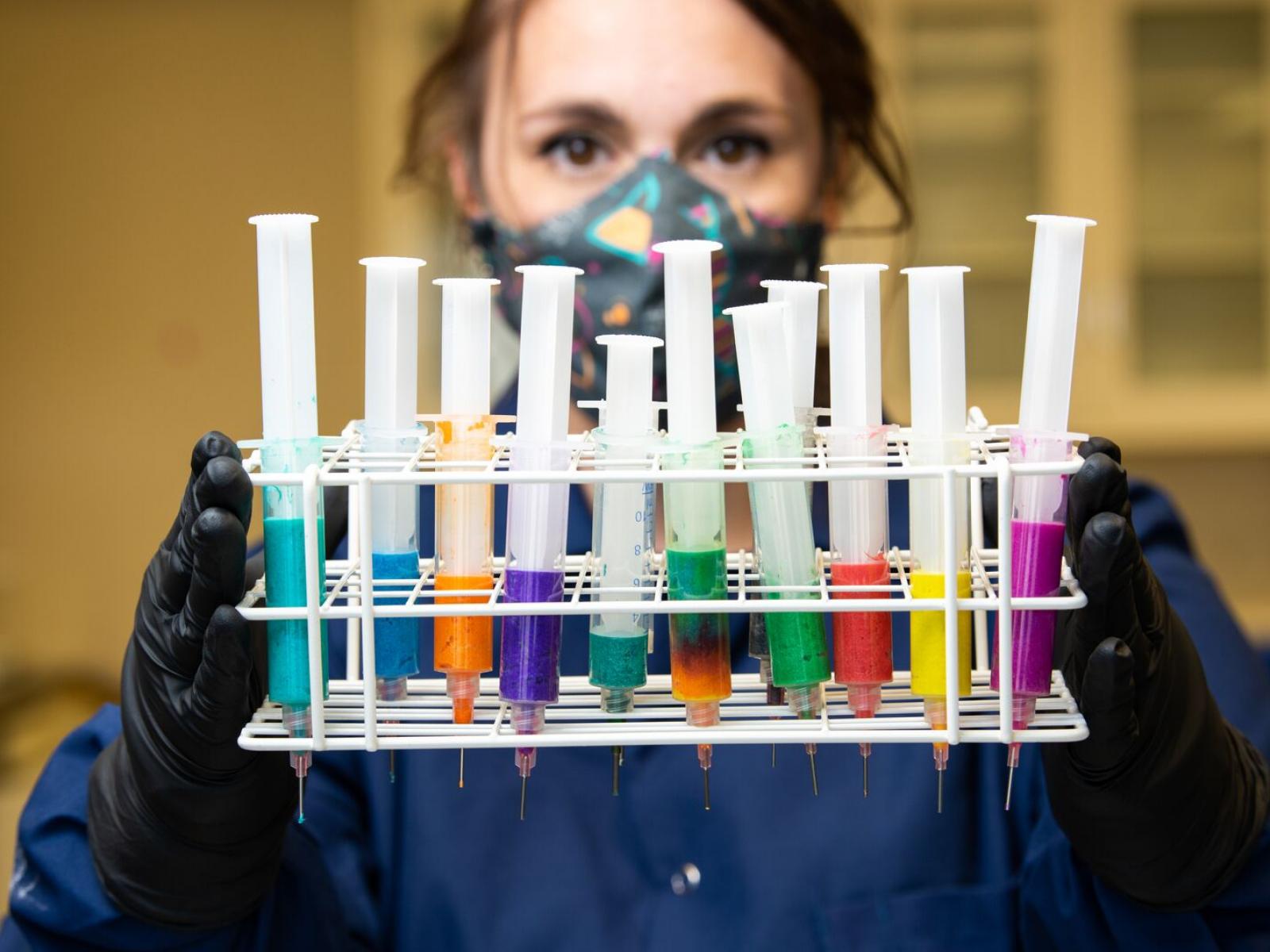 Woman in lab coat holding rack of bioinks
