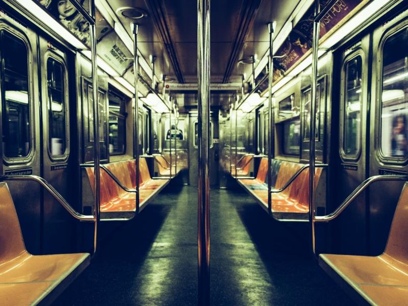 Photograph of empty subway cark with multicolored plastic-looking seats.