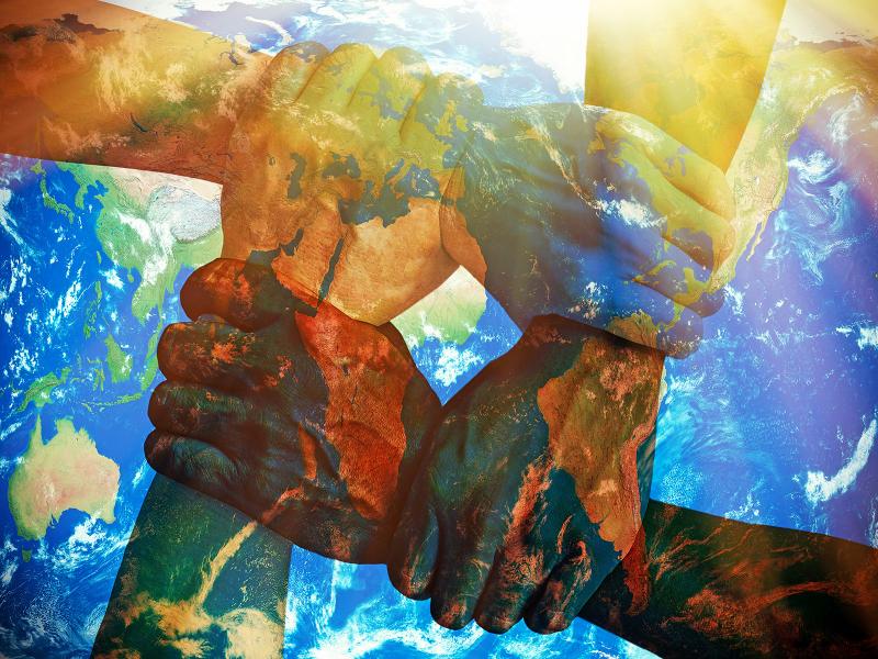 An illustration shows different colored hands united over an image of the earth