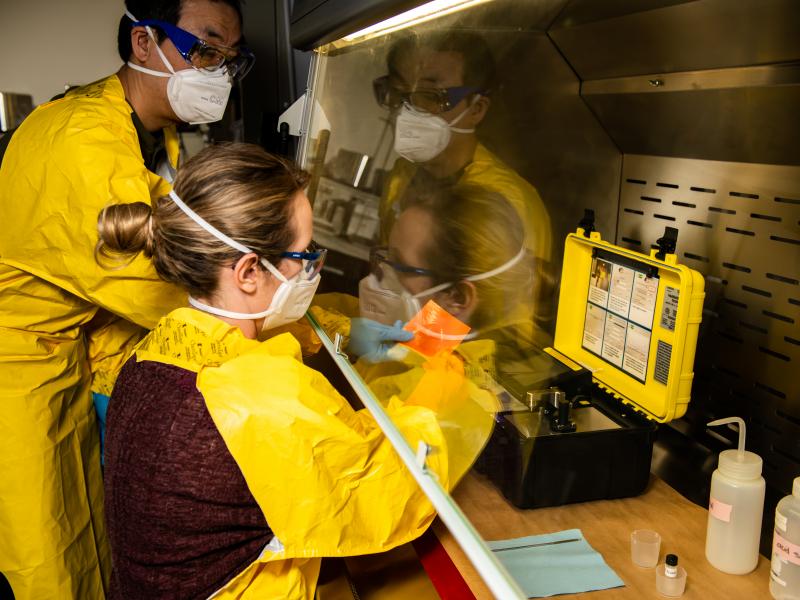 Two researchers in protective equipment at a containment hood.