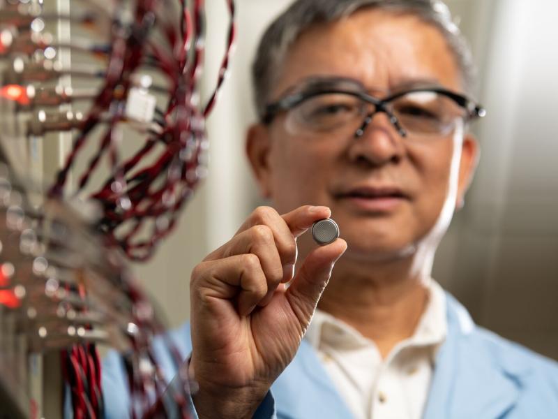 Jason Zhang holds a coin-sized sodium-ion test battery