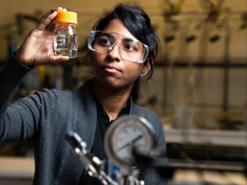 Photo of a researcher holding up a small container.