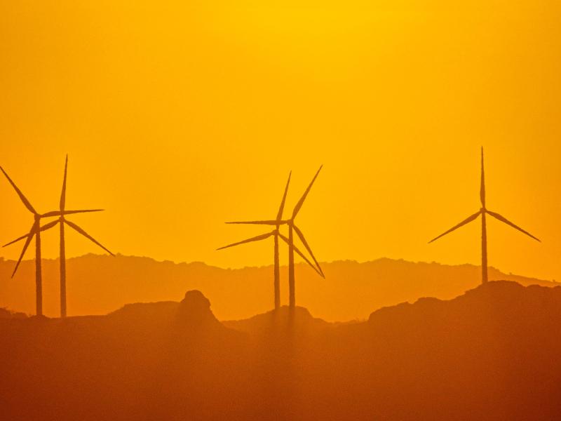 Photograph of wind turbines in a warm colored haze