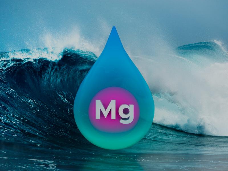 A droplet of water containing a sphere labeled magnesium superimposed on a photograph of a wave