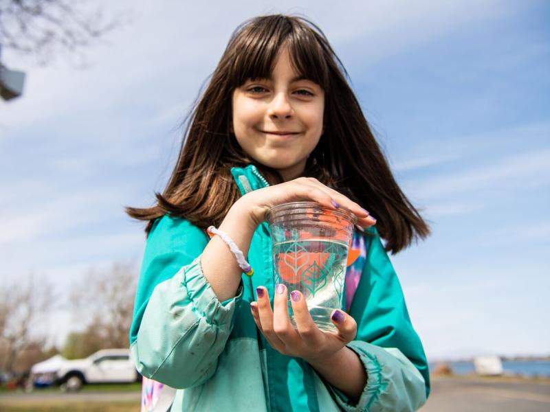 Photo of a young student holding a cup of water containing a fish