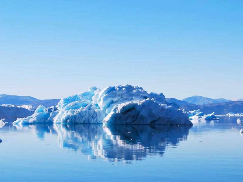 A photograph of an iceberg on a frosty coast, all surrounded by light.
